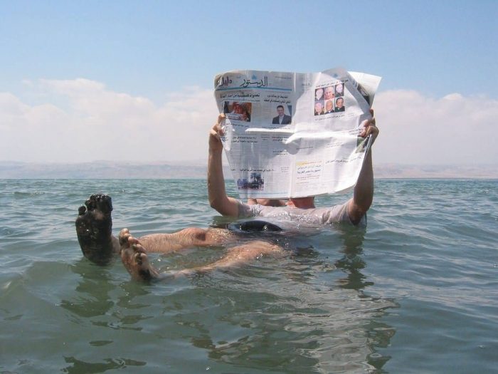A Man Reading A Newspaper In The Dead Sea